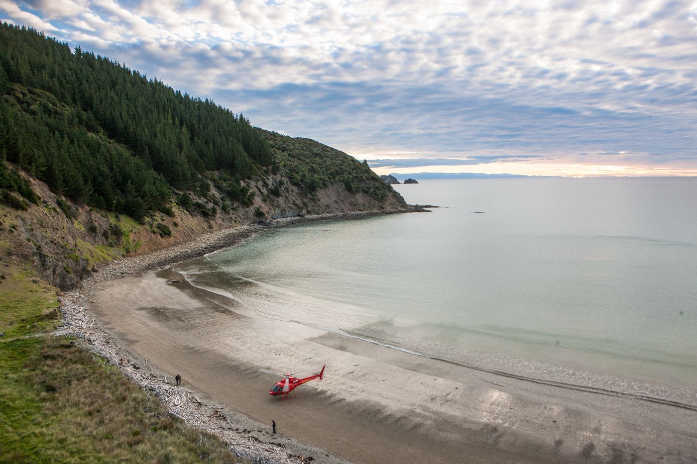 Red helicopter landed on an empty beach in a quiet bay