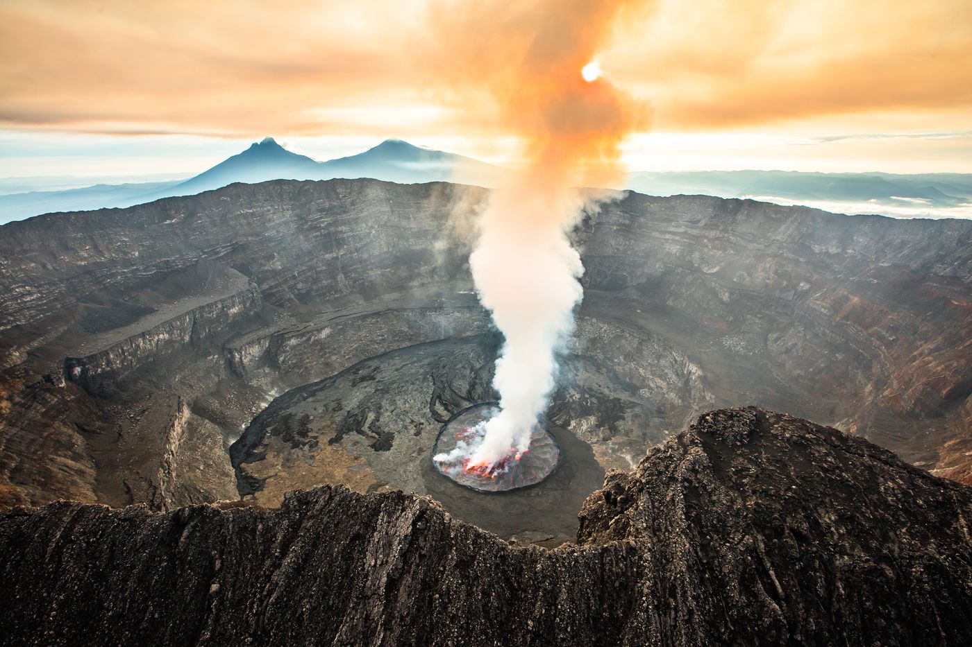 Aerial view of an active volcano with a plume rising from its crater