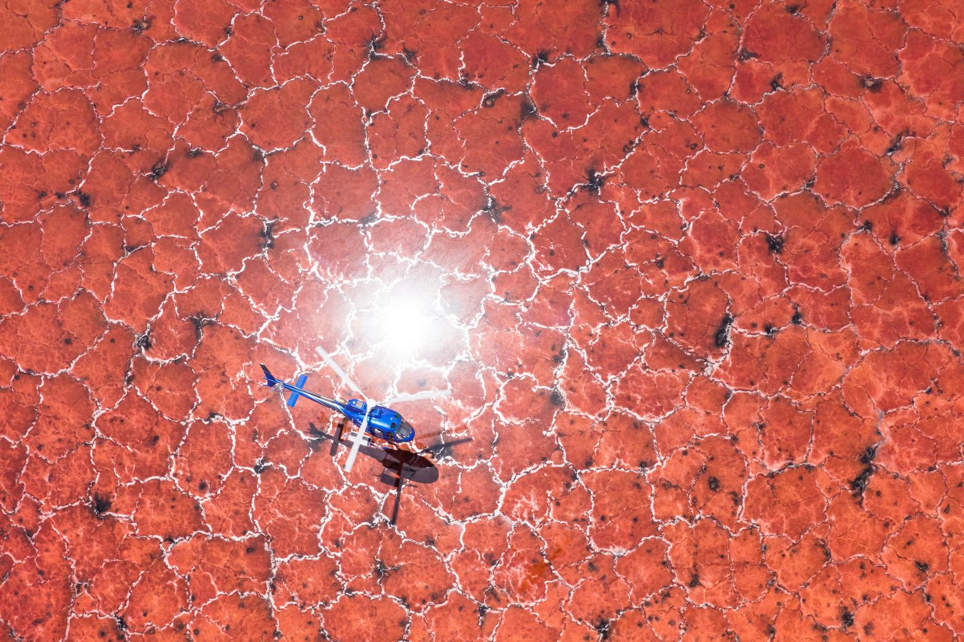 Aerial view of a helicopter over a red salt lake