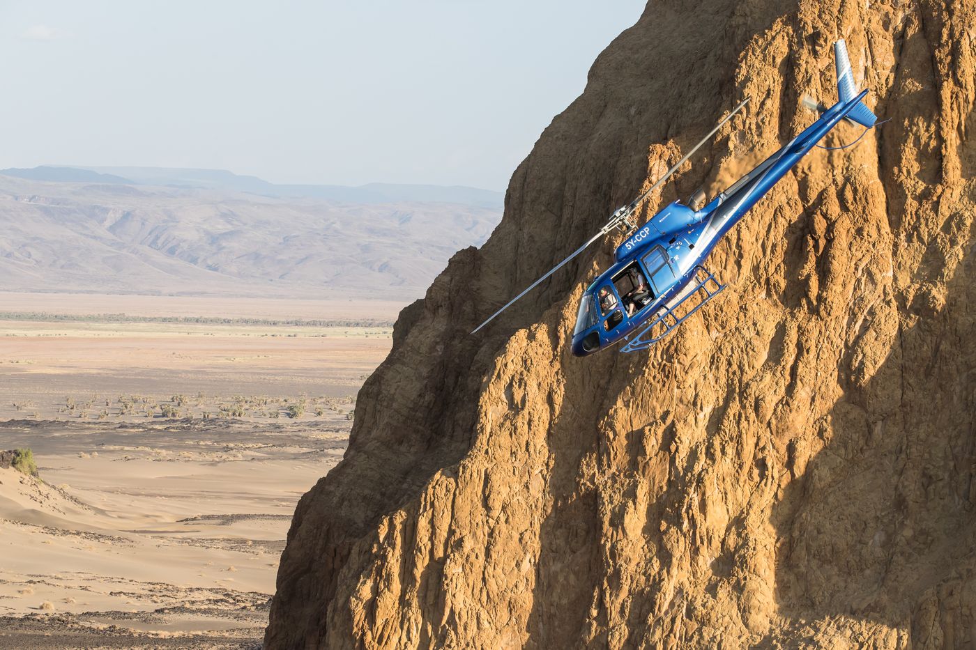 Helicopter flying close to a sheer rock cliff