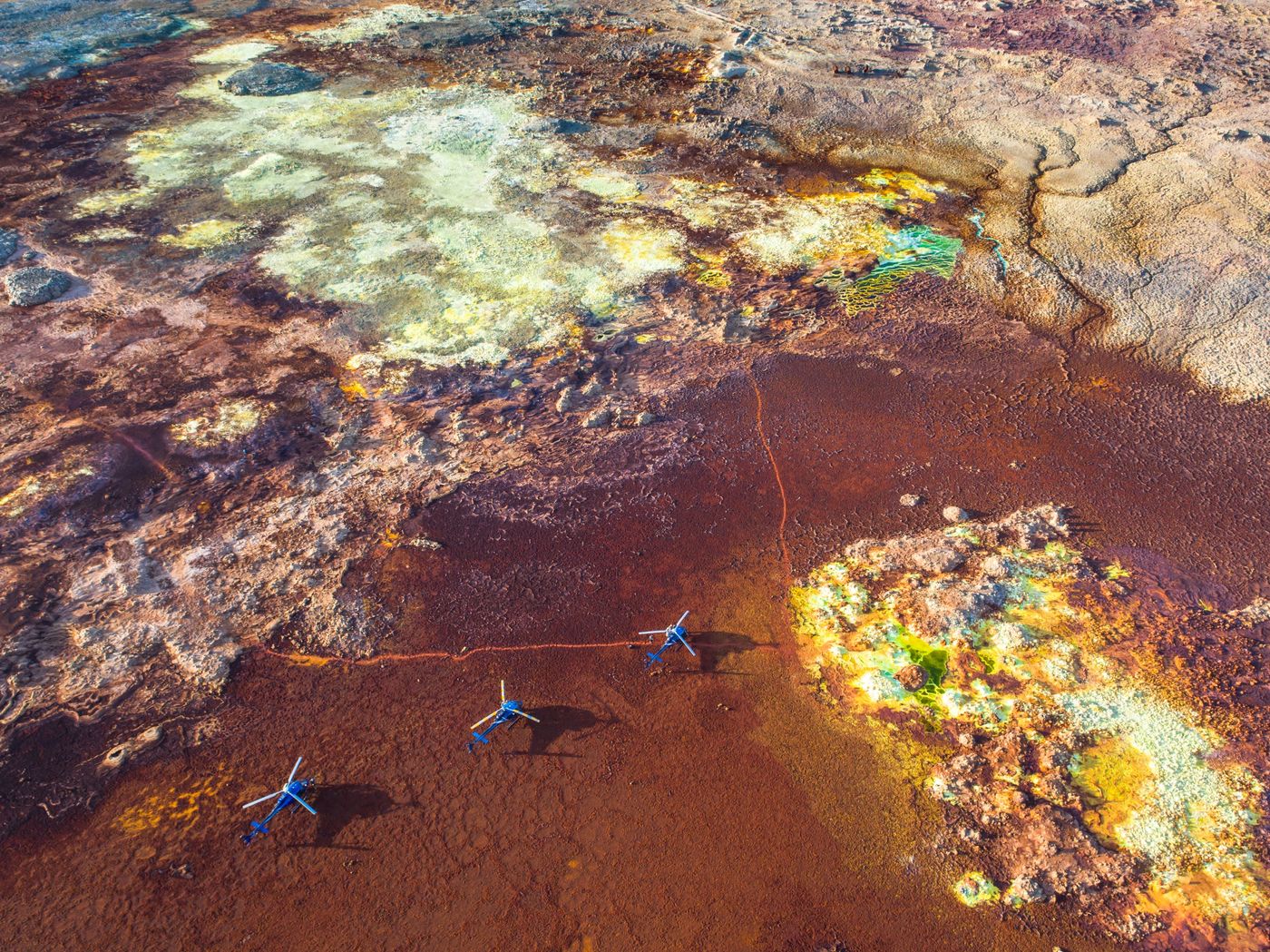 Three helicopters on the coloured mineral fields of Dallol, Ethiopia
