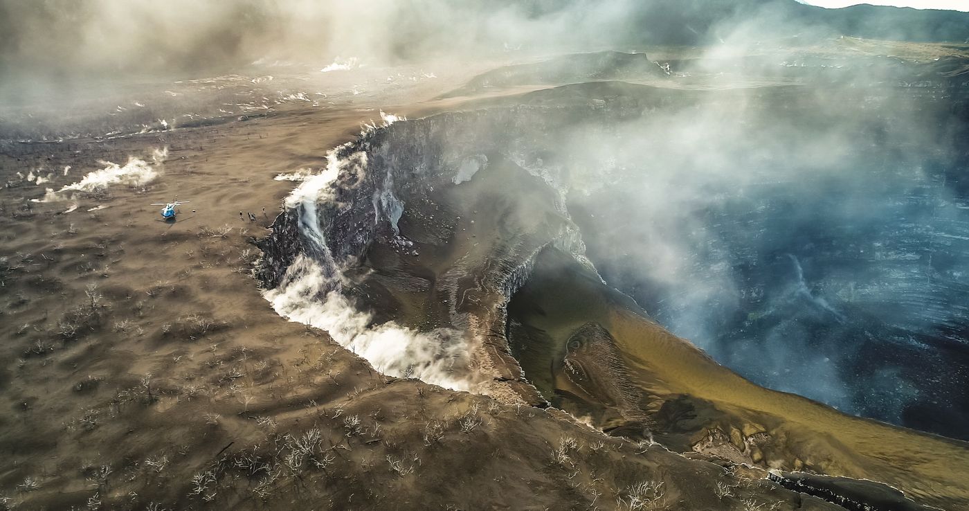 Helicopter parked near the steaming rim of an active volcano