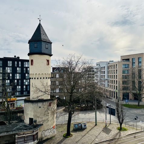Das Bild zeigt den Blick auf die Galluswarte, einem bekannten Wahrzeichen im Herzen Frankfurts, und die Mainzer Landstraße aus dem Wartezimmer der Praxis Neurologie Galluswarte.