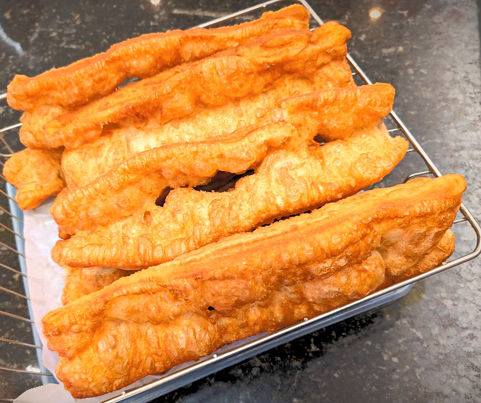 Golden-brown fried dough sticks on a wire rack, set on a dark countertop. The crispy texture is highlighted by bright lighting.