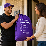 A Roundabout driver handing a purple laundry bag to a customer at her door.