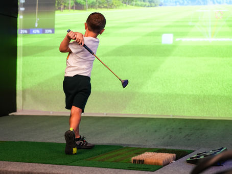 Child swinging a golf club on a Golfzon simulator at ChampionZone Virtual Golf in Edinburgh Indiana