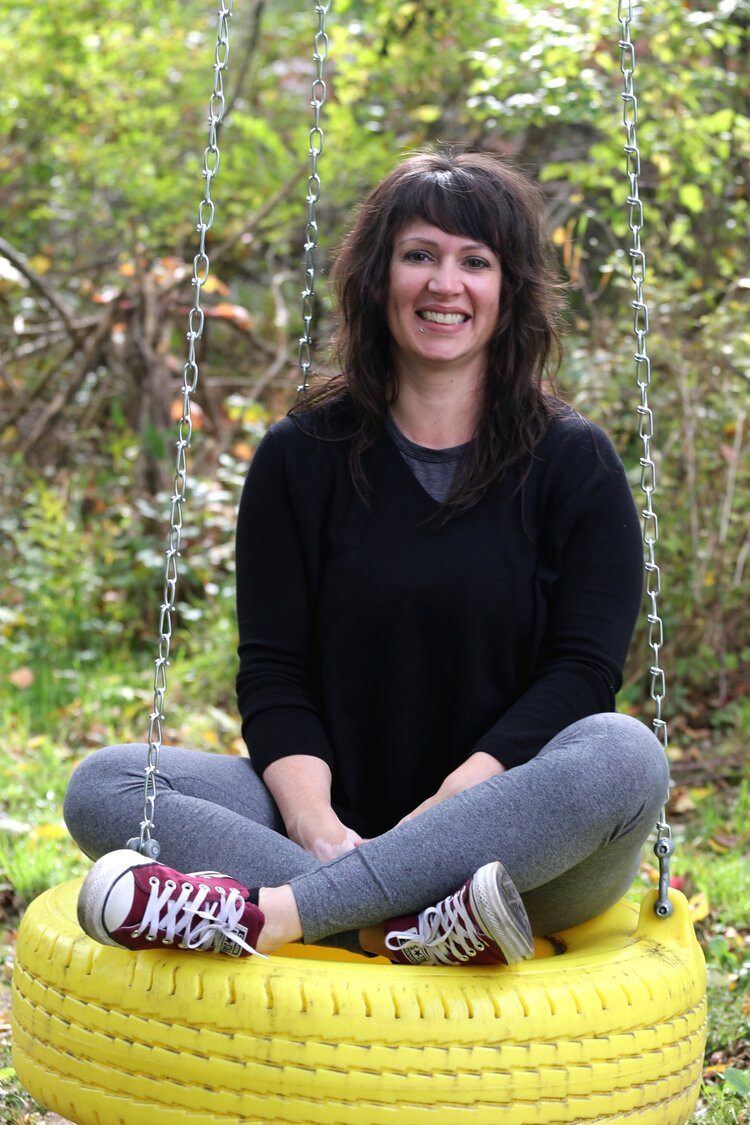 Carmen Coyne, sitting on a tire swing
