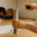 a person's hand showing up that he/she is holding the handheld coffee grinder