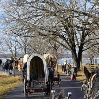 Covered Wagons with horses are pictured traveling down Parley Street in Nauvoo, Illinois toward the Mississippi River for The Annual Nauvoo Exodus Commemoration