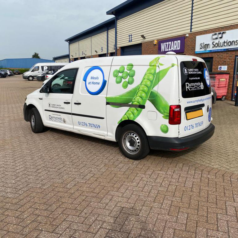 A photograph of a Renault Kangoo van with printed vinyl graphics on the rear quarters on the vehicle. This van has a pea pod on it.