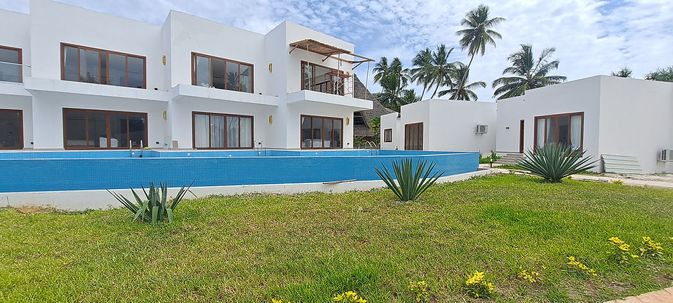 Close-up of a large empty swimming pool bordered by modern white villas with wooden window frames in
