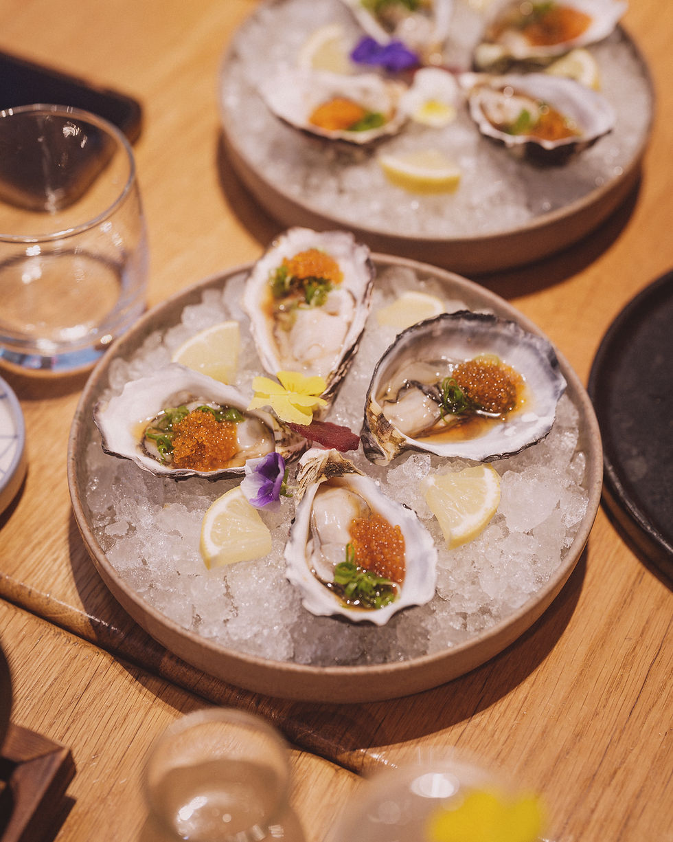 Fresh oysters on ice topped with roe, herbs and lemon