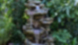 DIY water fountain using stone and pebbles flowing gently in a backyard garden setup.