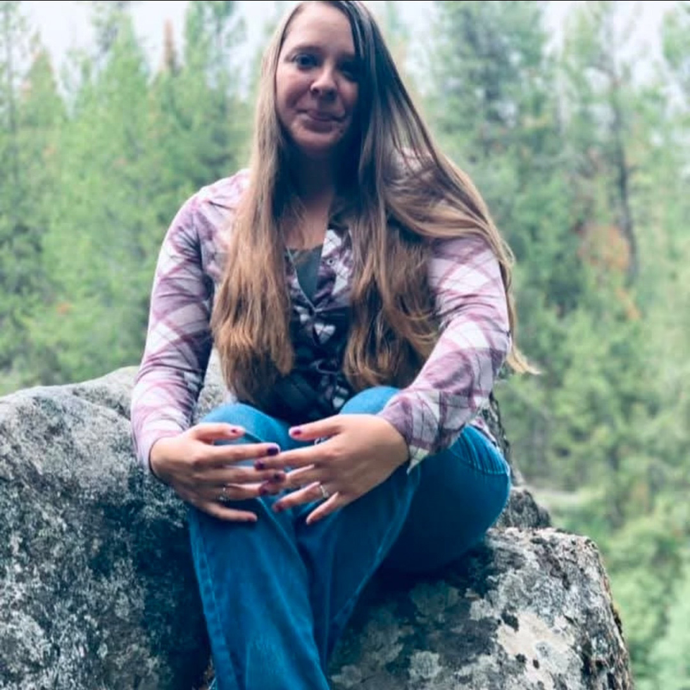 Portrait of KayLee Wangelin, Licensed Master of Social Work (LMSW) and Counselor at Visions Counseling & Education in Boise seen sitting on a rock in the woods.
