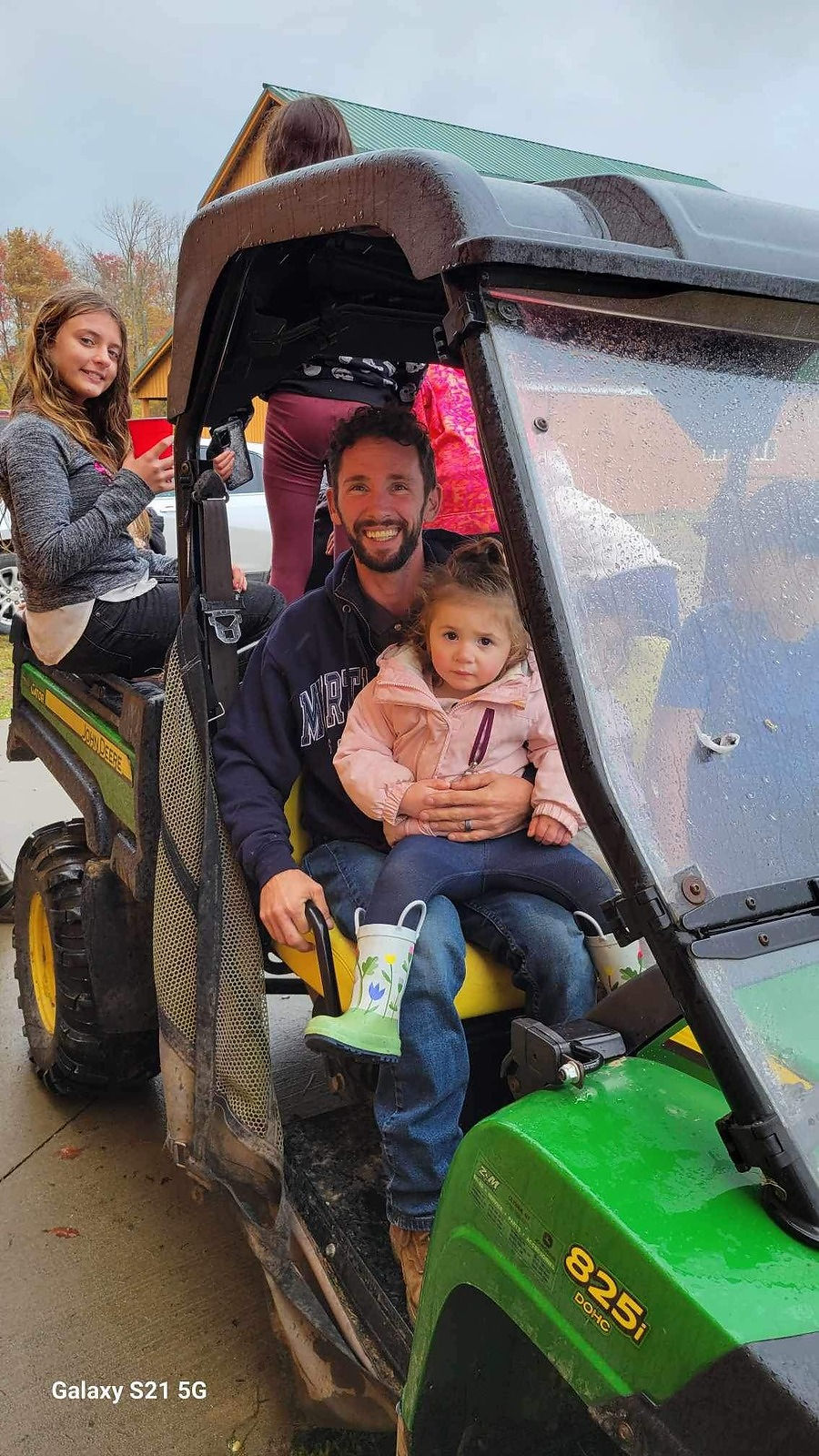 Man holding toddler in a utility vehicle, girl in back.