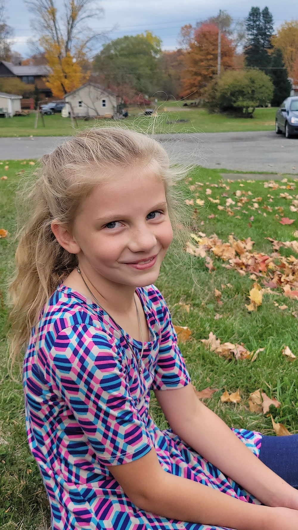 Young girl with blonde hair smiling outdoors