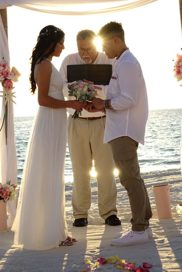 Couple and officiant with heads bowed in prayer during beach wedding ceremony at sunset in Panama City Beach