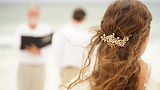 Bride looking dow at groom during beach ceremony
