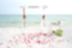 Beach wedding setup with redflowers, cake and champagne by the ocean 