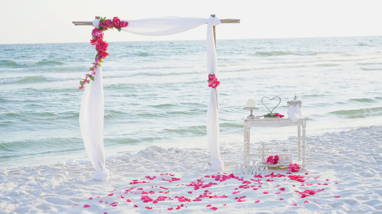 Beach wedding package set up with arch, cake and champagne by the ocean