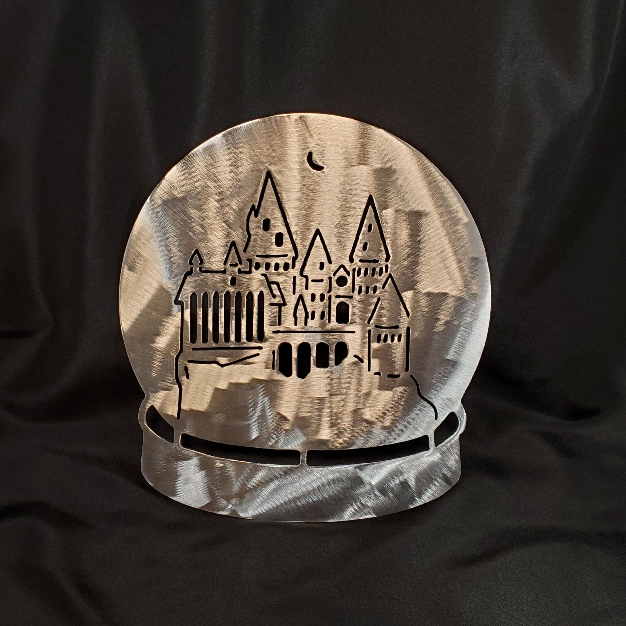 round metal sign with a flatter bottom castle carved out. black background