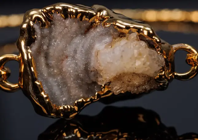 Nahaufnahme des eingefassten Natursteins mit kristalliner Oberfläche und goldfarbenem Rand.