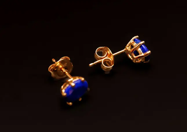 Ein Ohrstecker liegend, einer aufrecht stehend – zeigt Fassung und Verschluss der vergoldeten Ohrstecker mit Lapis Lazuli.