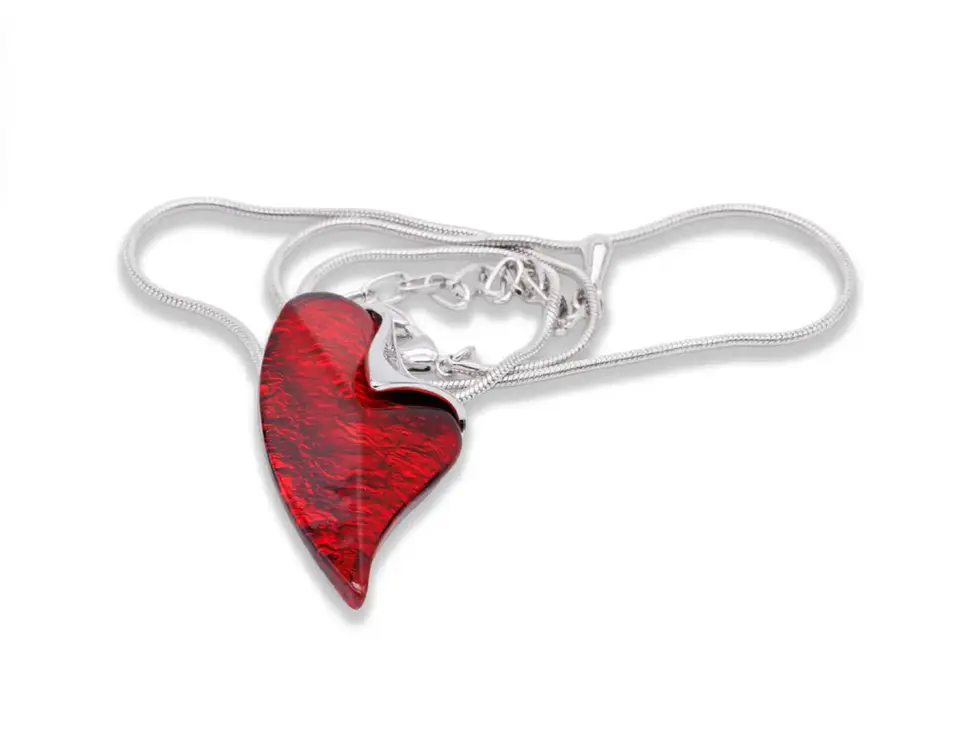 Silberfarbene Halskette mit asymmetrischem rotem Herzanhänger in strukturierter Optik auf weissem Hintergrund.