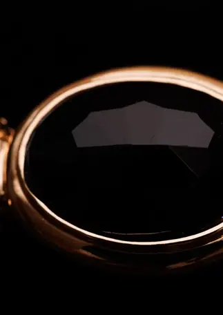 Armreif goldfarben mit schwarzem Stein – Detailansicht des facettierten schwarzen Steins.