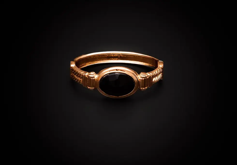 Armreif goldfarben mit schwarzem Stein – Frontalansicht auf schwarzem Hintergrund.