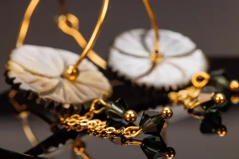Feine Details der hängenden Ketten mit grünlichen Kristallen und goldfarbenen Elementen unter der Perlmuttblume.
