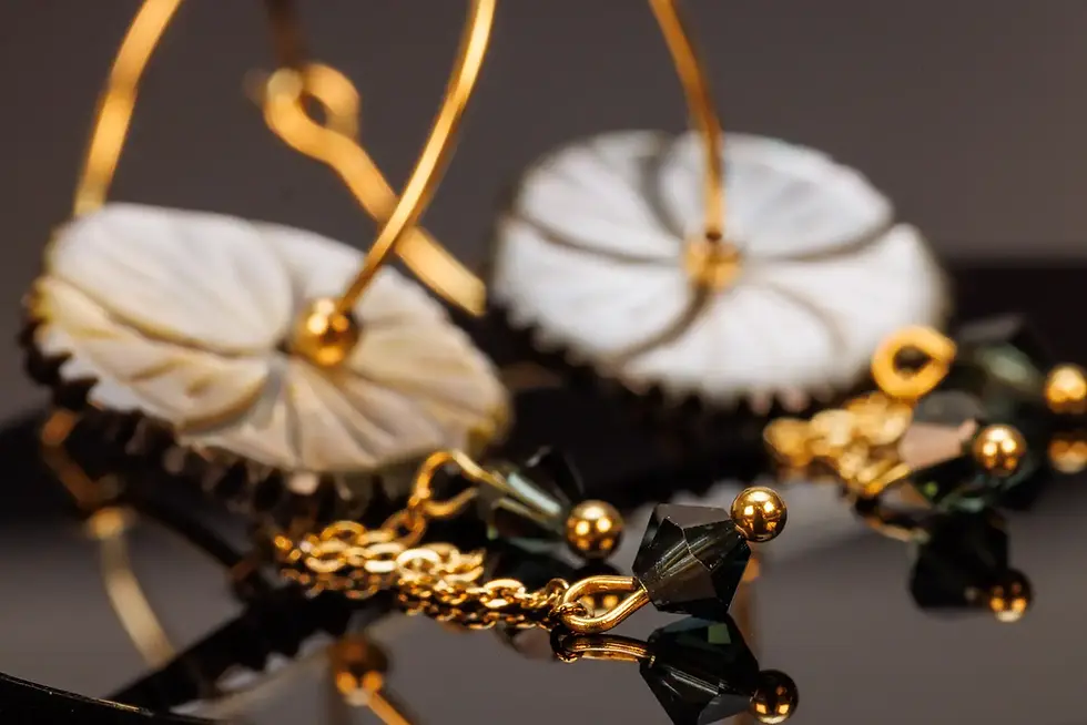 Feine Details der hängenden Ketten mit grünlichen Kristallen und goldfarbenen Elementen unter der Perlmuttblume.