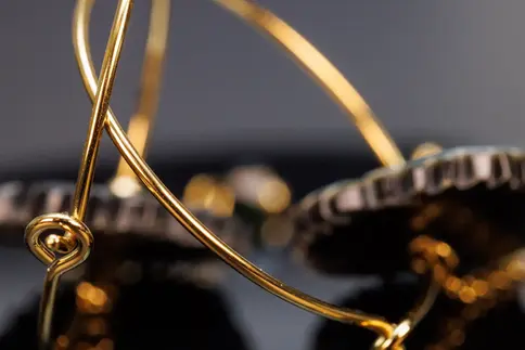 Makroaufnahme des Verschlusses der goldfarbenen Creolen mit elegantem Schwung.