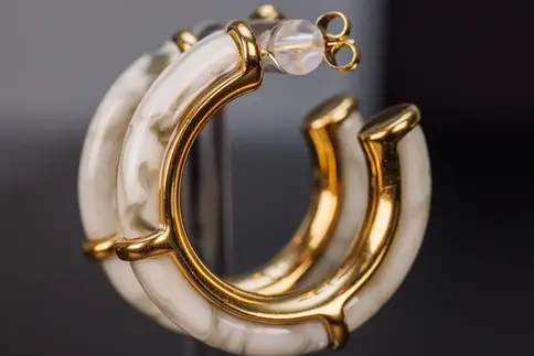 Paar goldfarbene Creolen mit weissem Acetat, modern und stilvoll kombiniert.