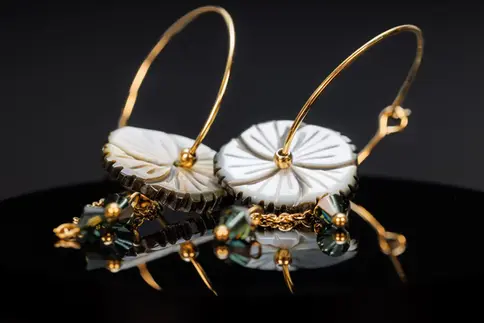 Zarte Creolen mit geschnitzter Perlmuttblume und goldfarbenem Reif – elegante Nahaufnahme von vorne.