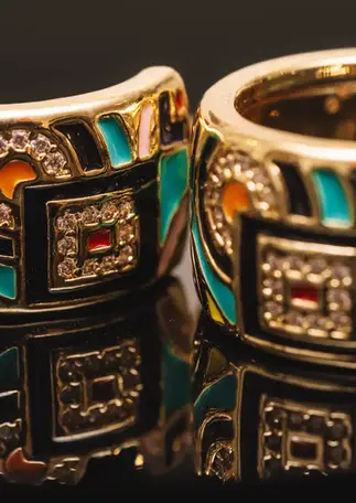 Halboffene Creolen goldfarben mit Emaille und Zirkonia, Nahaufnahme mit Spiegelung.