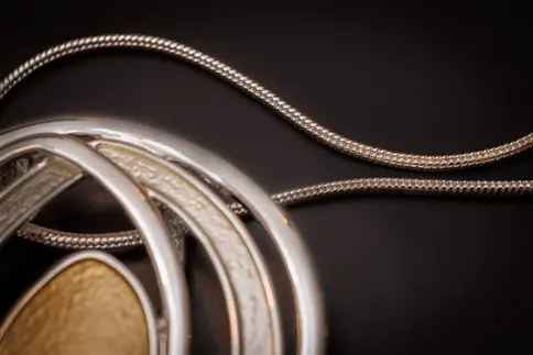 Feine silberfarbene Schlangenkette – Nahaufnahme der Textur und des Kreis-Anhängers.
