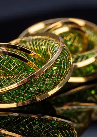 Goldfarbene Ohrringe mit grünem Glasstein – Frontansicht mit Gitterstruktur.