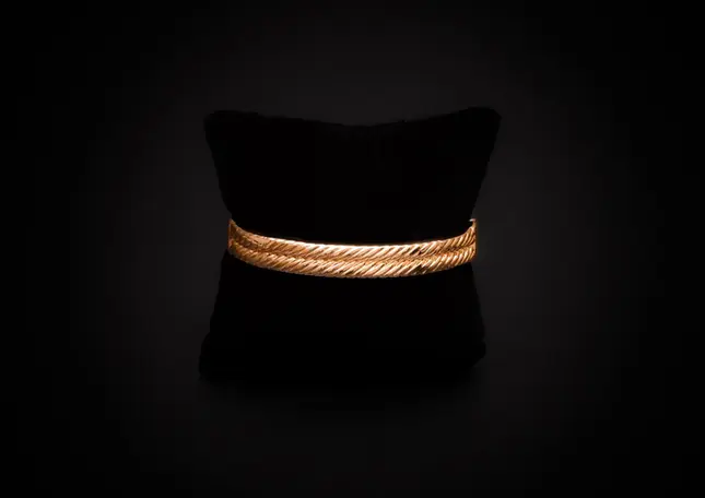 Armreif goldfarben mit schwarzem Stein – Rückansicht mit sichtbarer Rillenstruktur.