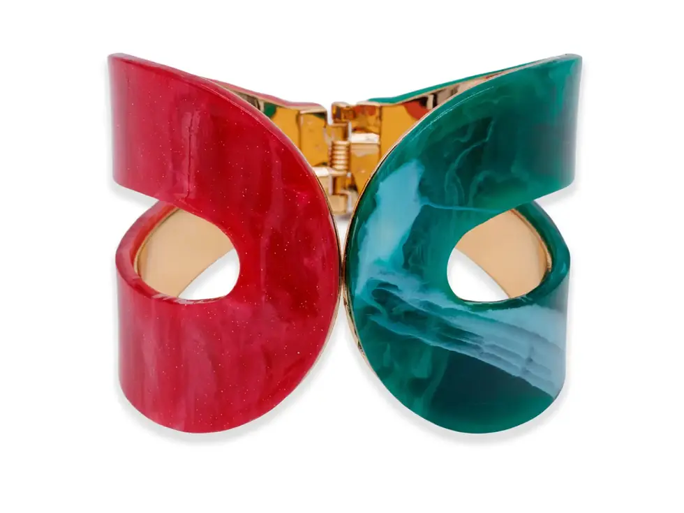 Armreif aus Acryl in Rot und Grün mit goldfarbenem Innenring auf weissem Hintergrund, auffälliger und moderner Schmuck.