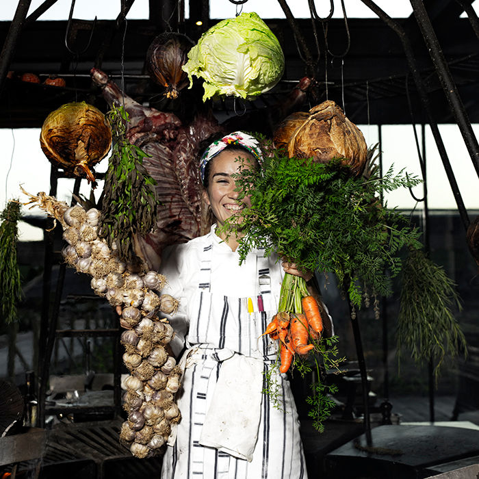 Portrait of chef Maira Ramos with vegetables surrounding her