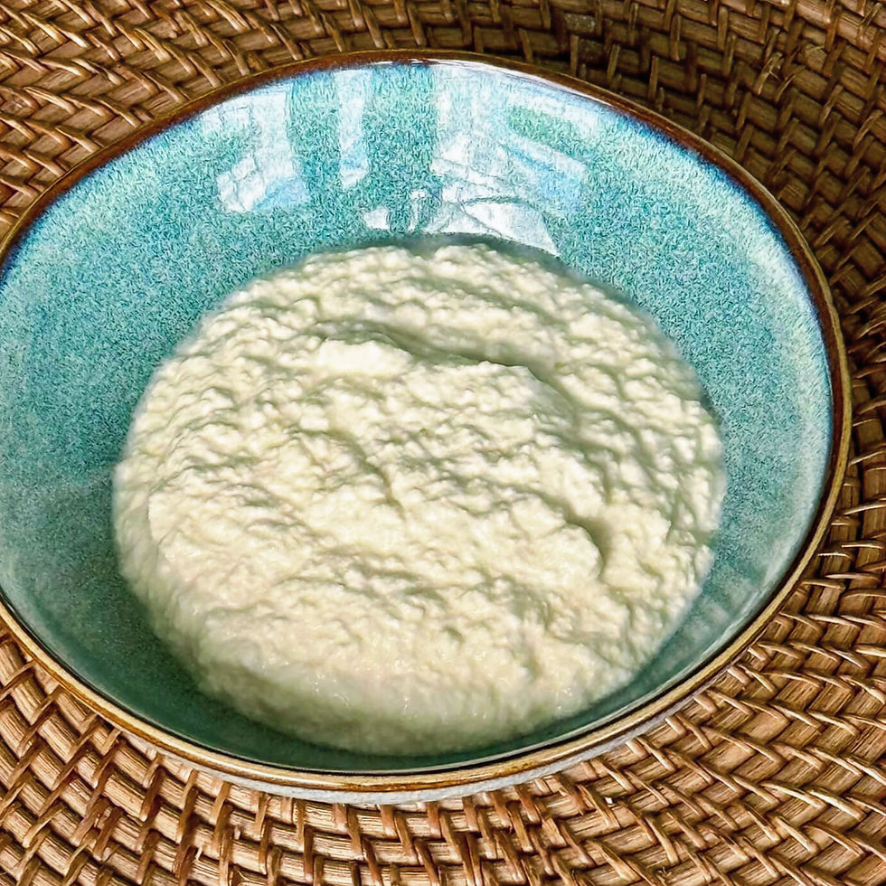 A bowl of thick white creamy ricotta in a blue ceramic bowl, resting on a woven basket surface, under natural light.