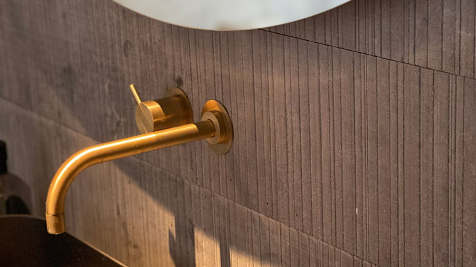 Brushed brass tapware and textured tile detail showing thoughtful material selection and craftsmanship in bathroom design