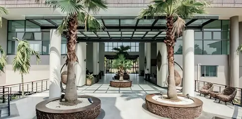 Open-air arrival lobby with palm planters and shaded circulation at Green Valley Residences, Mae Rim, Chiang Mai.