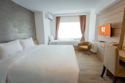 Standard guestroom at B2 Nakhon Sawan Premier Hotel showing integrated joinery, neutral finishes, and efficient layout.