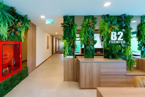 Lobby interior at B2 Grand Nimman Premier Hotel with reception joinery, planted feature wall with branding, neutral finishes, and clear circulation alignment.