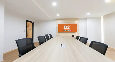Meeting room interior at B2 Don Mueang Premier Hotel featuring a central board table, integrated power access, neutral finishes, and restrained brand feature wall.
