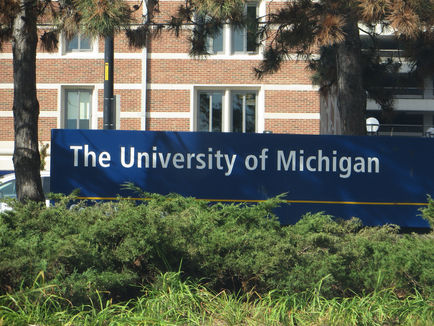 A red and white brick building with a blue sign with white letters which reads The University of Michigan