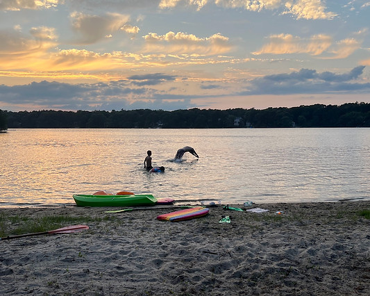 Private sandy beach with kayaks, paddle boards, and fire pit at Lake Shore Cottage