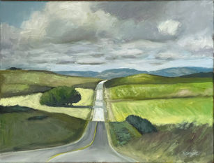 country road with green fields, mountains, and clouds